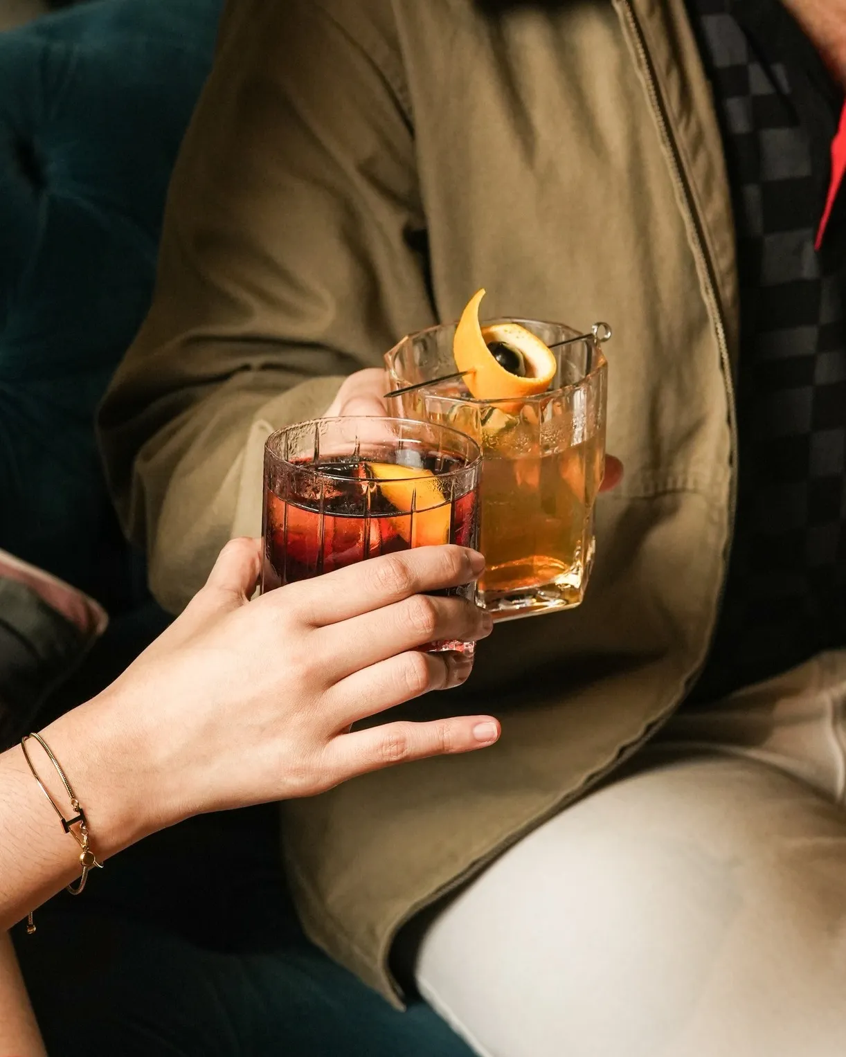 Two guests raising amber cocktails in the bar