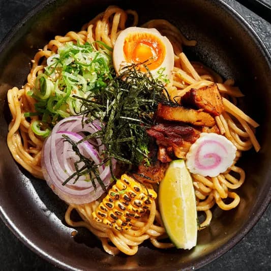 Abura soba with pork, egg, seaweed, corn and noodles in a black bowl